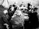 Group of expedition members and other people sitting around a large table, eating