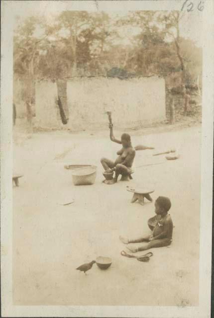 Woman pounding grain, and child seated on ground