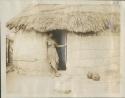 Woman standing in doorway of hut