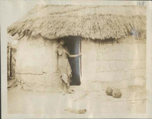 Woman standing in doorway of hut