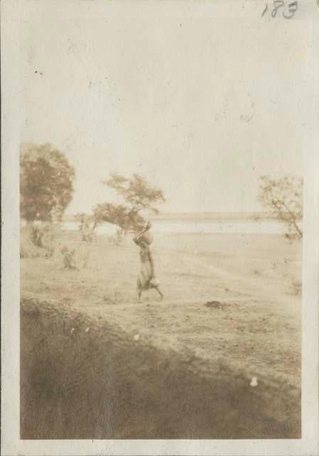 Woman carrying water, river in background