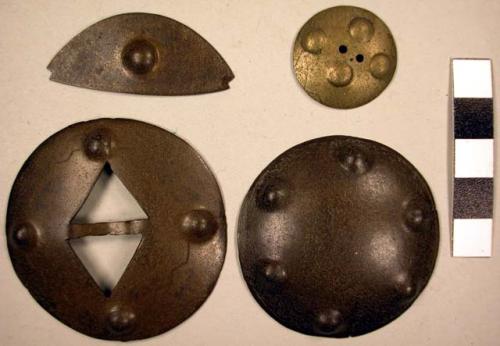 Silver ornaments. 3 are circular and have round designs, 1 is eye-shaped