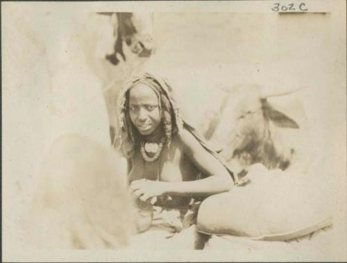 Woman seated, cattle in background