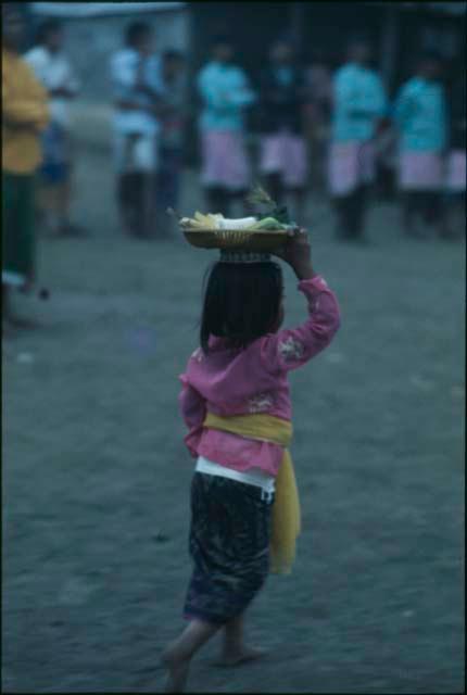 Child carrying a basket on their head