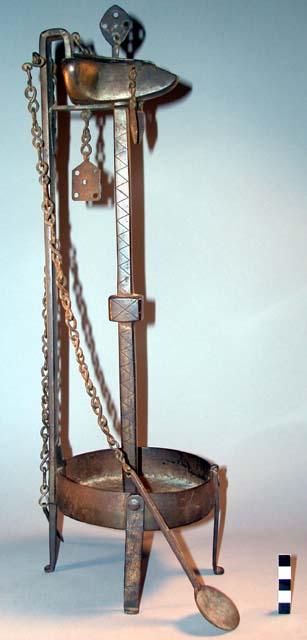 Iron oil lamp standing on four legs, sharp object and spoon +