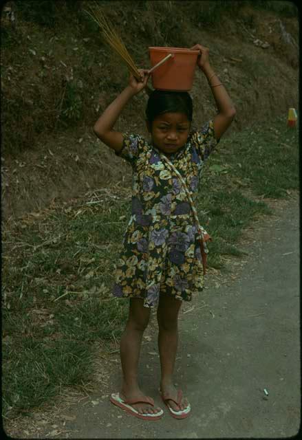 Child carrying a pot on her head