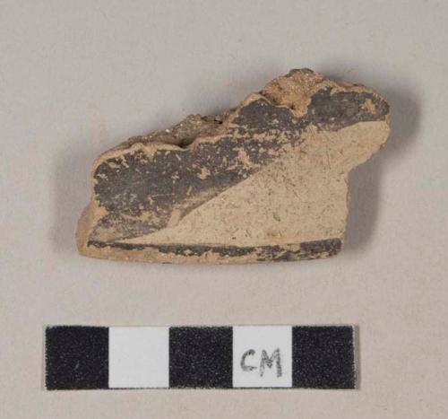 Coarse red bodied earthenware rim sherd, with buff slip and black slipped stripes, reduced core