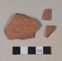 Red bodied earthenware rim sherds, with red slip and possible brown slip along rim; three sherds crossmend