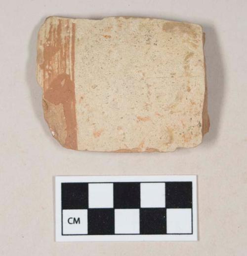 Coarse red bodied earthenware rim sherd, with buff slip and red slipped stripes