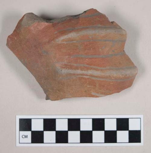 Red painted potsherd with incised relief decoration