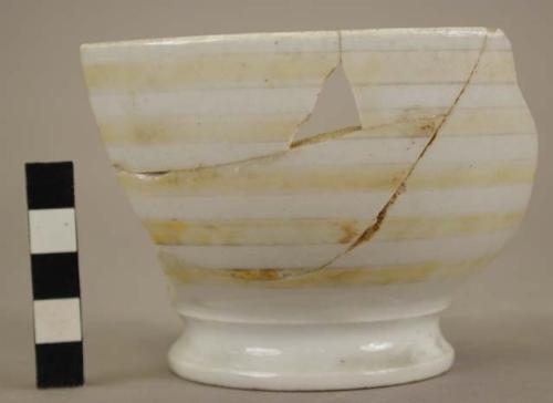 Part of white china bowl with yellow horizontal stripes; restored