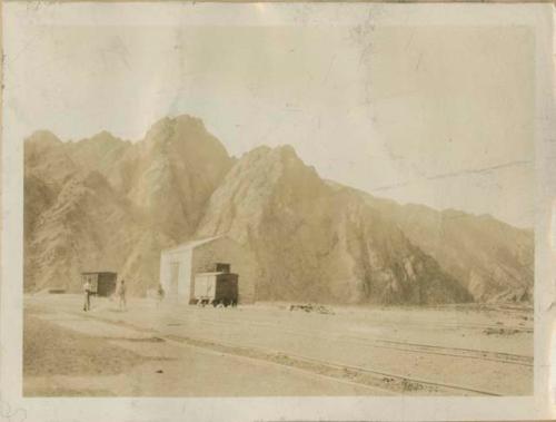 Buildings and train tracks in front of rocky hills