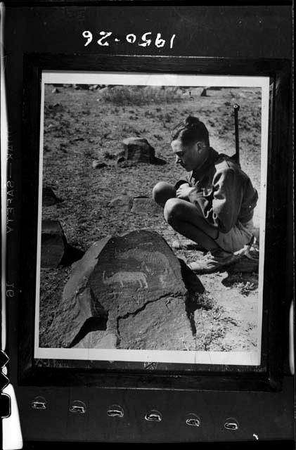 Boy looking at a petroglyph of two rhinos