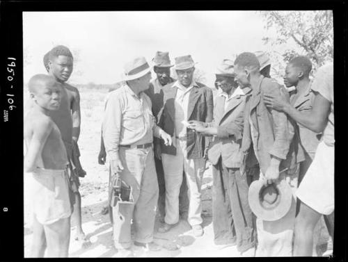 Group of people standing and talking with William Hartley, Edward Hartley and Laurence Marshall, holding a camera