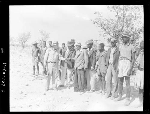 Group of people standing and talking with William Hartley, Edward Hartley and Laurence Marshall, holding a camera