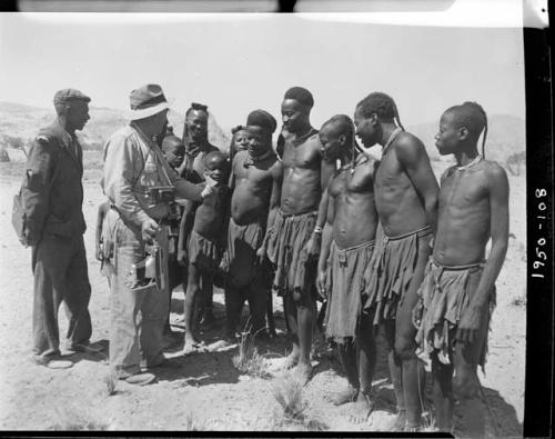 Group of people standing and listening to Laurence Marshall, who is holding a camera