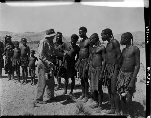 Group of people standing and listening to Laurence Marshall, who is holding a camera