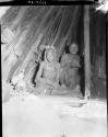 Woman and man sitting inside a hut