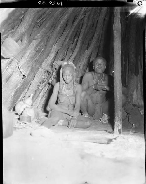 Woman and man sitting inside a hut