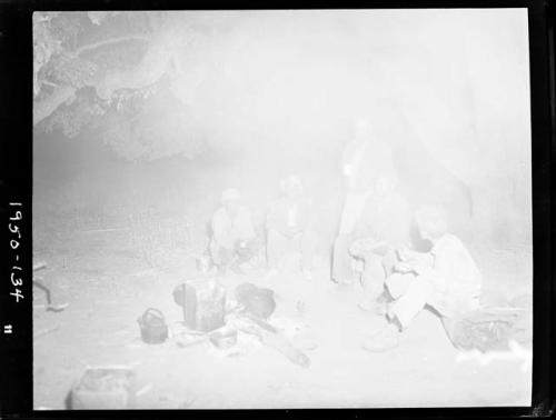 Expedition members sitting and standing around a cooking fire, including Edward Hartley, Laurence Marshall and John Marshall