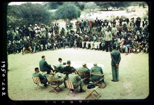 Indaba at Omajetti, Herero chief, with a large group of people sitting and standing behind him, addressing expedition members, including Colonel Hoogenhout, John Neser, Laurence Marshall and John Marshall