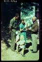 Laurence Marshall showing a Polaroid photograph to the Hartmann family at their farm