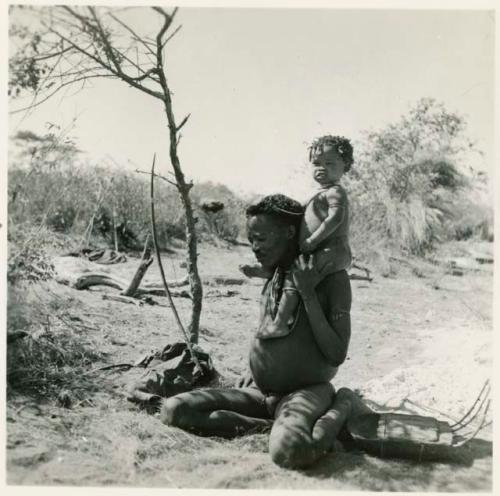 "Gao Hunchback" sitting and holding his child on his shoulder, with a //guashi lying on the ground next to him