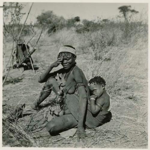 Woman of Band 11 with her child tied in her kaross, sitting