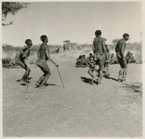 Group of men dancing, with a child dancing beside her father