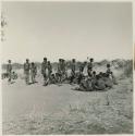 Group of men performing a curing dance, cutting across a circle of women