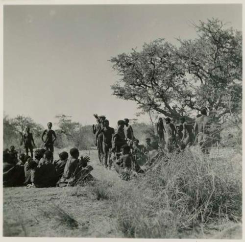 Group of people dancing, with women sitting and clapping