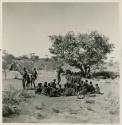 Men and two boys dancing through a circle of women sitting, view from the top of an expedition truck