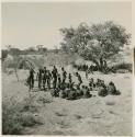 Men dancing in front of a group of women sitting