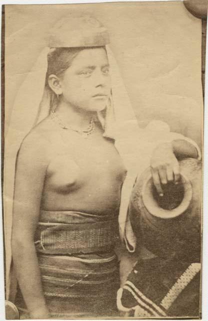 Studio portrait of Mixtec woman with arm drapped over pottery