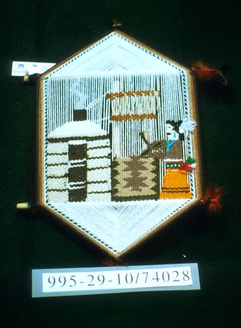 Wallhanging picture of a weaver in hexagonal loom-frame