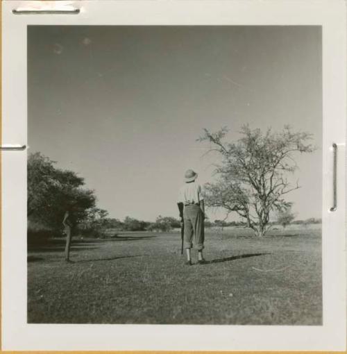 Expedition member standing in a vley (small pan), holding a gun