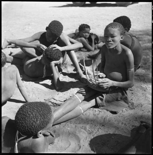 ≠Toma (son of Gau) playing the //guashi, with other boys lying on the ground next to him