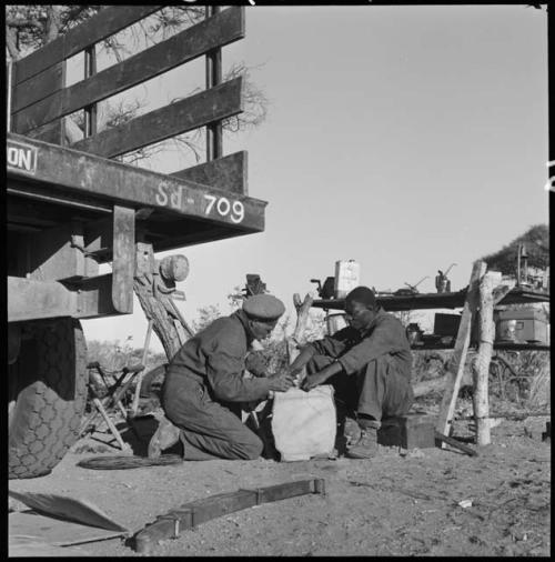 Heinrich Neumann and another expedition member repairing a stool