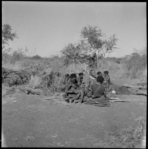 Group of women sitting, one of them wiping off a child who has defecated