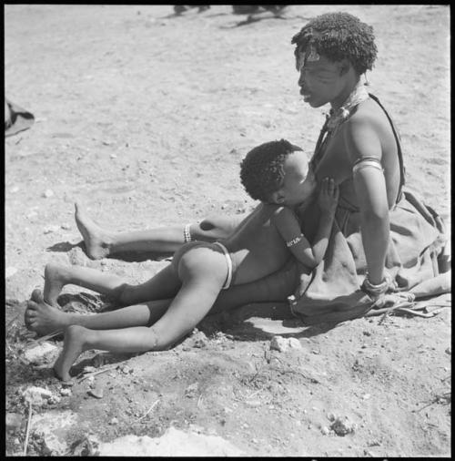 //Kushay (wife of "/Qui Navel") sitting, with "Little ≠Gao" lying on her leg nursing