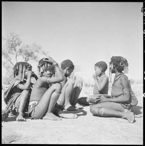 Girl playing a //guashi, sitting with a group of girls and boys