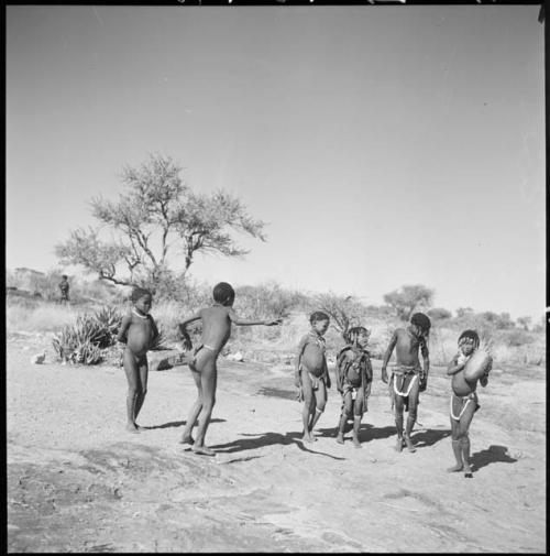 Boys and girls dancing, with a girl playing the //guashi; "Little N!ai" is standing fourth from the left