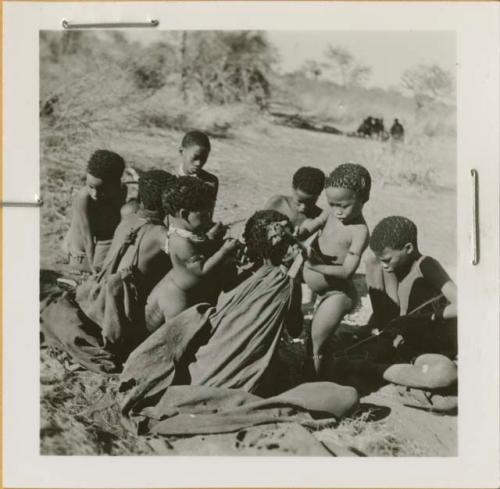 Group of people sitting around a fire, including /Naoka ("Gao Medicine's" first wife), her son /Gaishay, "≠Gao Lame," and Gao (son of ≠Gao and Khwo//o-/Gasa)