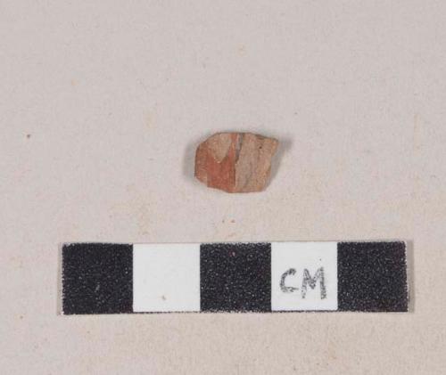 Red bodied earthenware rim sherd, with red slip and black slipped stripes, wheel thrown