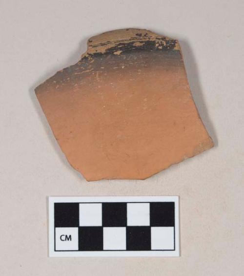 Red bodied earthenware rim sherd, with red and black slip, wheel thrown
