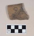 Coarse brown bodied earthenware rim sherd, with brown slip, reduced core, molded protrusion