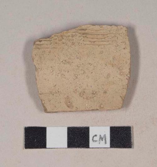 Coarse red bodied earthenware body sherd, with buff slip and incised lines