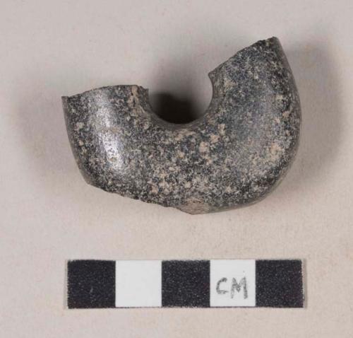 Semi-circular ground stone fragment with central hole, possible handle or fragment of a ring