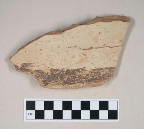 Coarse red bodied earthenware rim sherd, with buff slip and black slipped decoration, reduced core