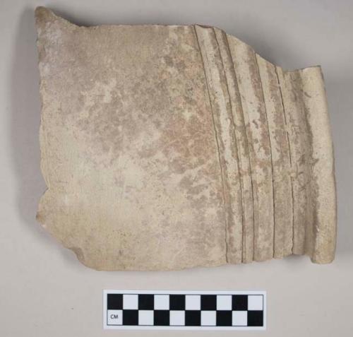Coarse red bodied earthenware rim sherd, with buff slip and molded decoration